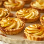 Mini apple tartlets with caramel drizzle on a platter